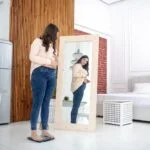 Woman looking at her body in the mirror