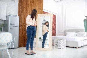 Woman looking at her body in the mirror